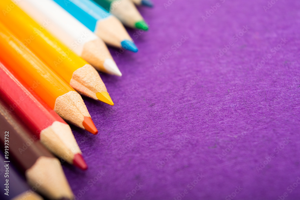 Nine multicolored pencils on a purple felt background. Different colored pencils with space for text. Back to school. Art lessons. Nine multicolored pencils on a purple felt background. Different colored pencils with space for text. Back to school. Art lessons.