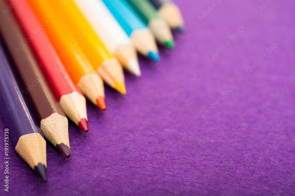 Nine multicolored pencils on a purple felt background. Different colored pencils with space for text. Back to school. Art lessons.