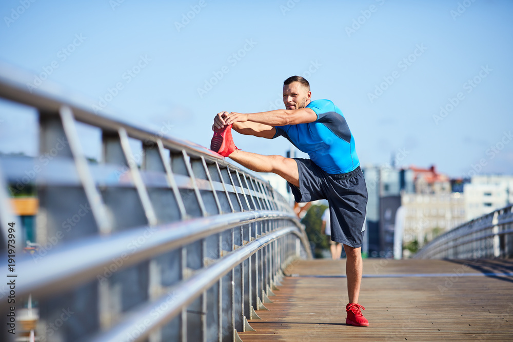 athletic man stretching during an outdoors workout