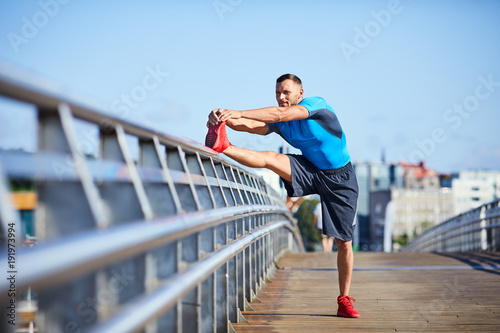 athletic man stretching during an outdoors workout © baranq