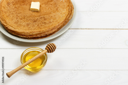 Fried crepes with honey on white wooden table. top view with copy space photo