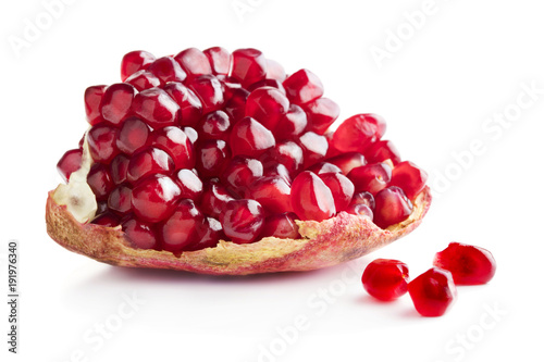 piece of ripe pomegranate with few separate ceeds isolates on white background
