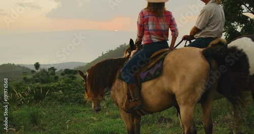 Couple horseback riding at sunset photo