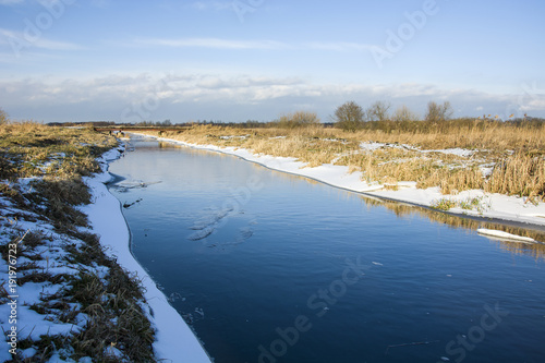 Fototapeta Naklejka Na Ścianę i Meble -  River and dry grass on the shore covered with snow