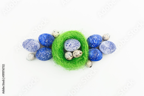 Blue speckled easter eggs and quail eggs in nest on white background. Flat lay, top view. Happy Easter.