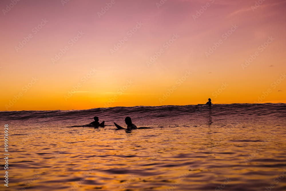 Sunset in Bali and surfers waiting for wave in ocean