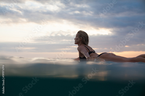 sportswoman lying on surf board in ocean