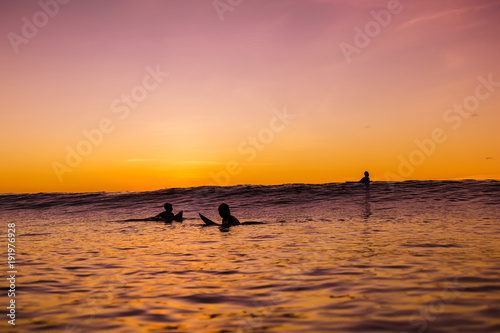 Sunset in Bali and surfers waiting for wave in ocean