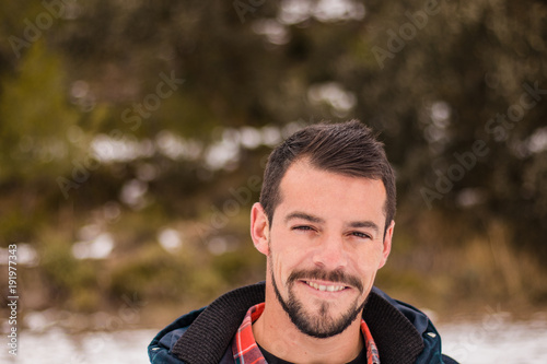 Young man with beard laughing in nature