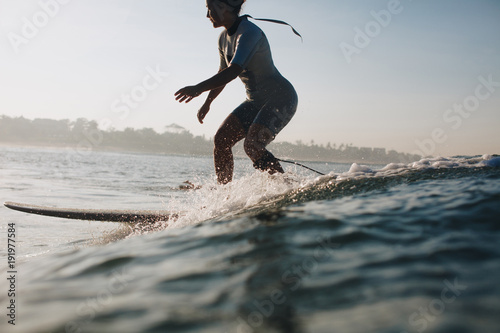 silhouette of sportswoman surfing in ocean  coastline on background