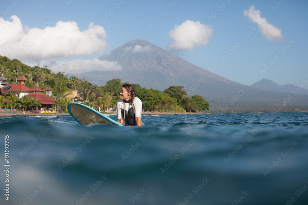 woman sitting on surf board in ocean, coastline on background woman sitting on surf board in ocean, coastline on background