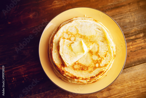 Russian Maslenitsa, Shrovetide, pancake week, carnival, shrove, pancake day. a stack of pancakes with butter upstairs on plate, on wooden background, close-up