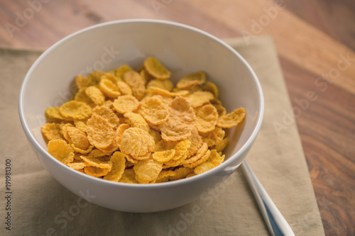 corn flakes in white bowl for breakfast on table