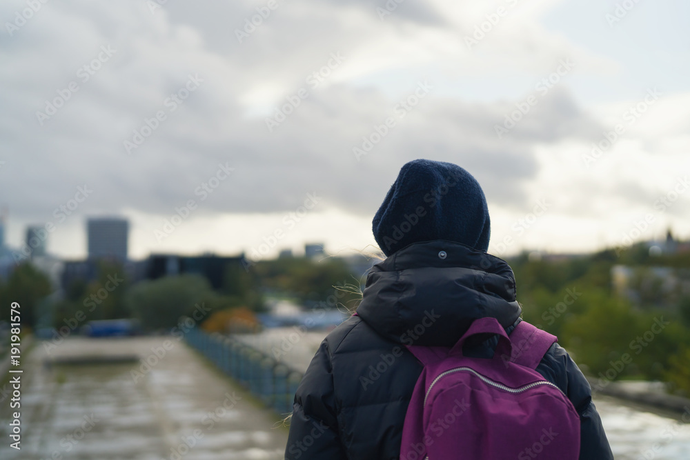 teen girl walking in the city in autumn from behind teen girl walking in the city in autumn from behind