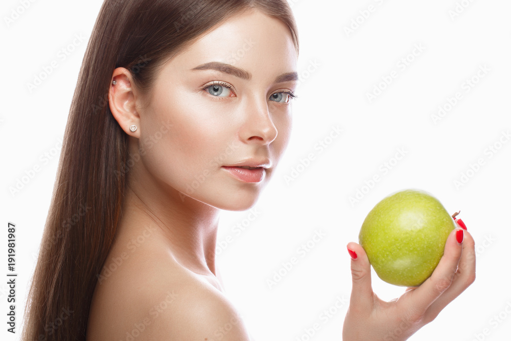 Beautiful young girl with a light natural make-up and perfect skin with apple in her hand. Beauty face. Picture taken in the studio on a white background. Beautiful young girl with a light natural make-up and perfect skin with apple in her hand. Beauty face. Picture taken in the studio on a white background.