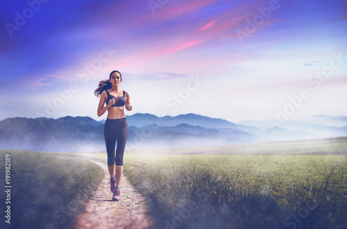 Young fit woman running through misty path
