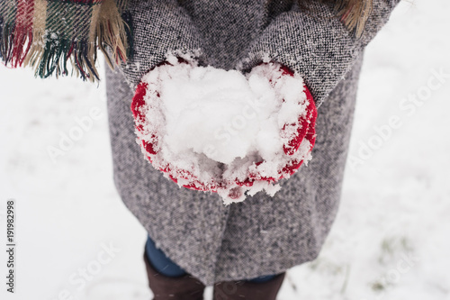 Girl wearing red covered gloves holding snow with Merry Christmas greeting photo