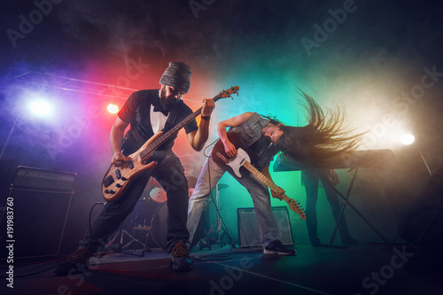 Rock band performs on stage. Guitarist, bass guitar and drums. © Voloshyn Roman