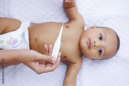 Mother Measures The Temperature Of Her Baby Using Digital Thermometer 