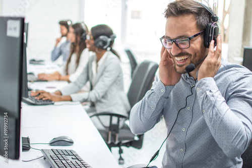 Smiling customer service executive with headset working in call center. photo