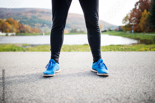 Young runner in autumn park standing on concrete path.