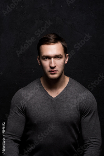 Handsome tough guy on a black background. Portrait. Brawn. Gray sweater. Force. Masculinity. © Дмитрий Днепровский