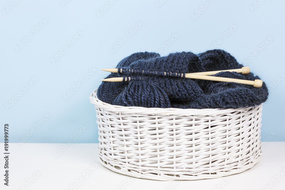 Obraz premium Basket with woolen yarn and knitting needles, balls of thread. Copy space for text.