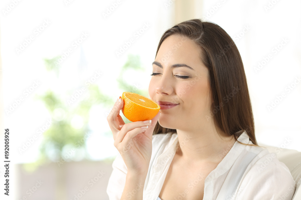 Woman smelling half orange at home Woman smelling half orange at home