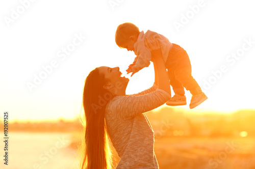 Cuadro en lienzo Mother raising her kid son at sunset
