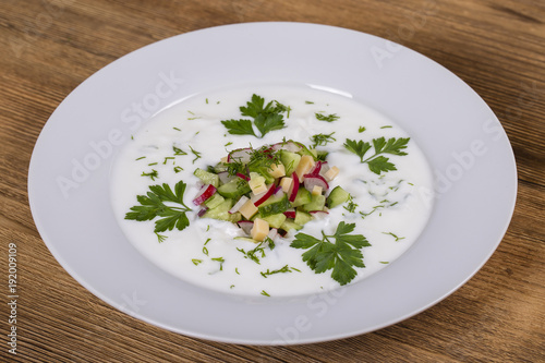 Okroshka. Summer light cold vegetable soup with cucumber, radish, eggs and dill on a wooden table. A traditional dish of russian or ukrainian cuisine.