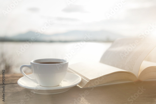 Cup of coffee and book on a wooden table