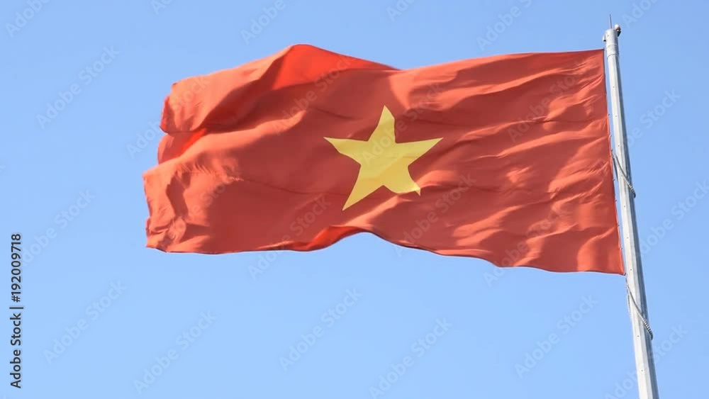 Red flag with yellow star. Flag of Vietnam on the blue sky background. Vietnam popular country for tourism.