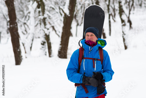 Happy snowboarder stands in the winter forest