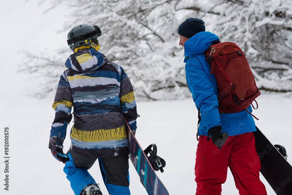 Two happy snowboarders is walking, talking and laughing