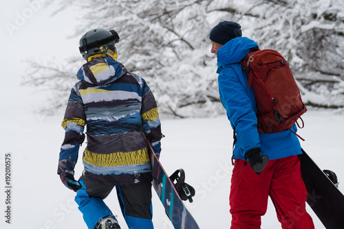 Obraz na płótnie Two happy snowboarders is walking, talking and laughing w salonie