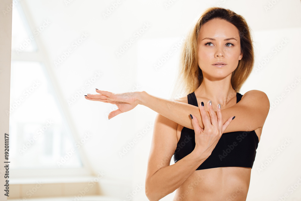 sporty young woman stretching hands at yoga class in fitness studio