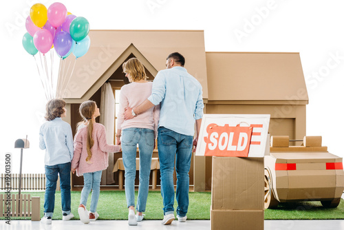 back view of young family moving into new cardbord house isolated on white photo