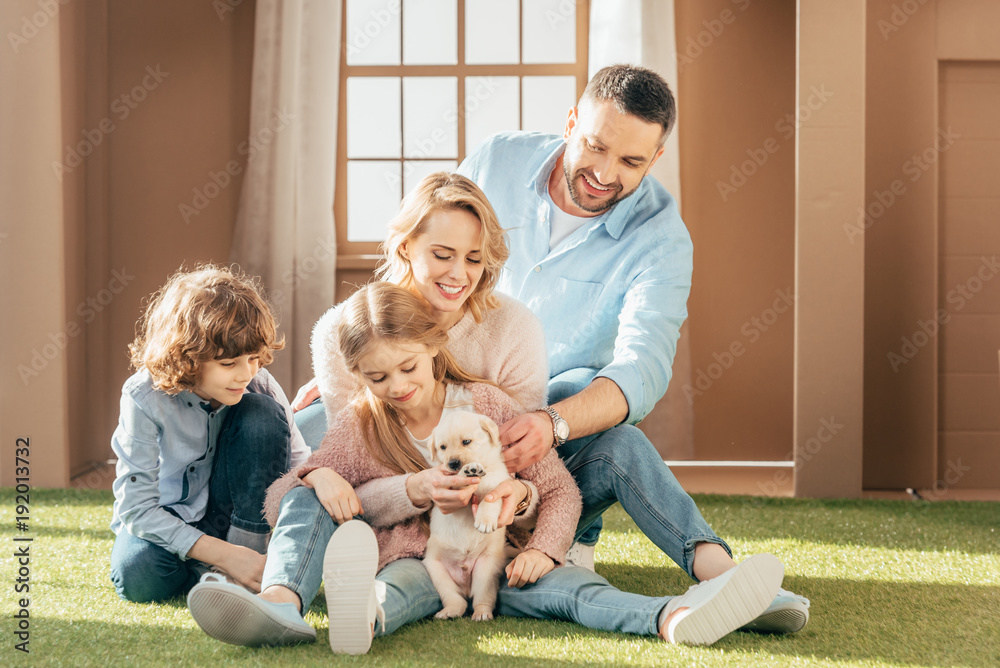 Φωτογραφία beautiful young family with yellow lab puppy on yard of cardboard house
