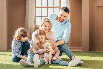 beautiful young family with yellow lab puppy on yard of cardboard house