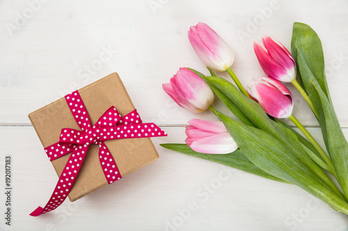 Women's day. Pink tulips and a gift on white background, top view