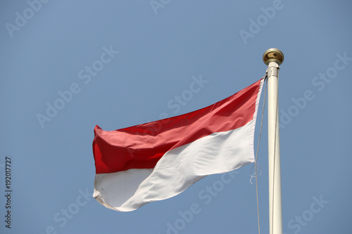 National flag of Indonesia on bright blue sky background. Blown away by wind. Indonesia is one of the ten Association of South East Asian Nations. photo