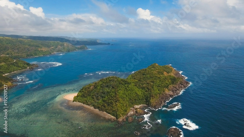 Fototapeta Naklejka Na Ścianę i Meble -  Coast of the tropical island Catanduanes with the mountains and the rainforest on a background of ocean with big waves. Aerial view: sea and the tropical island with rocks, beach and waves. Seascape