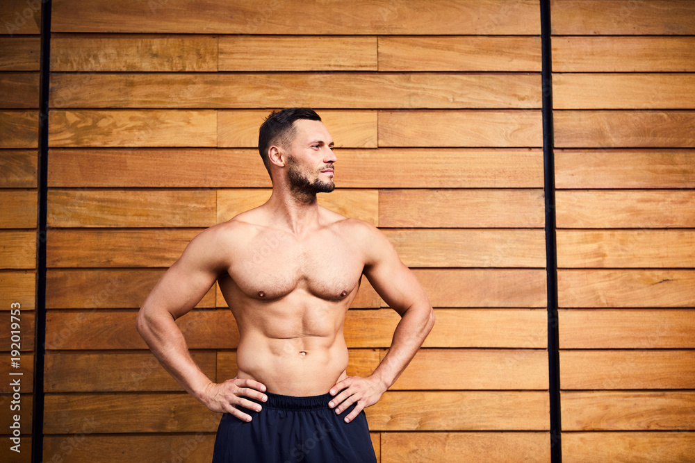 Φωτογραφία Portrait of a handsome athletic man looking away with hands on waist, standing i
