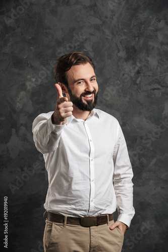 Bearded happy businessman pointing to you