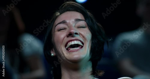 Woman laughing uncontrollably while watching a comedy movie at the cinema