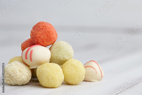 Assorted handmade truffle chocolates pyramid on white wooden table, copyspace