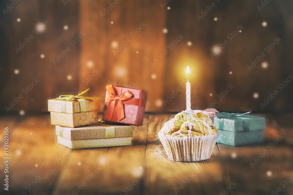 Birthday card. Cupcake with a candle and gift boxes on a wooden background.Holidays.