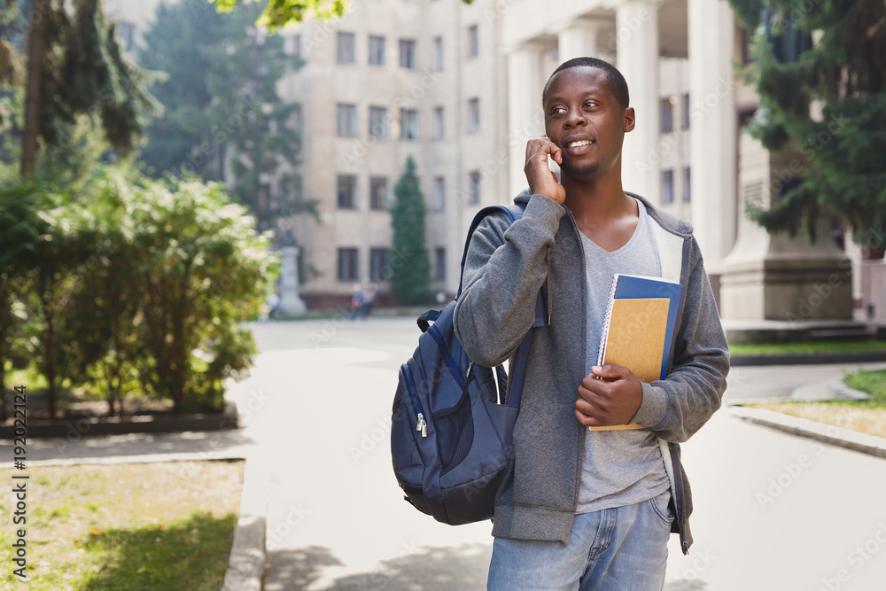 Obraz premium Happy african-american student talking on smartphone in campus