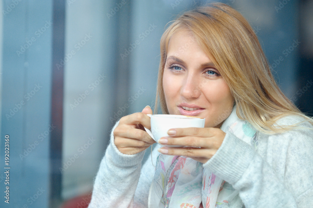 Portrait of a pensive girl drinking coffee and looking outdoors through a window Portrait of a pensive girl drinking coffee and looking outdoors through a window