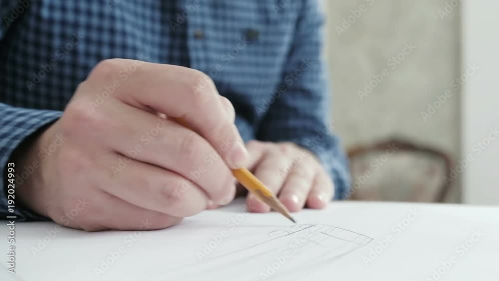 Artists hands drawing wooden pencil writes on paper. Young businessman painting something with pencil. Close-up of fashion designer drawing at office Artists hands drawing wooden pencil writes on paper. Young businessman painting something with pencil. Close-up of fashion designer drawing at office